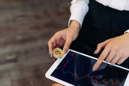 girl with a tablet in her hands. Girl hold a gold coin. Electronic money, Bitcoins, Crypto currency.の写真素材