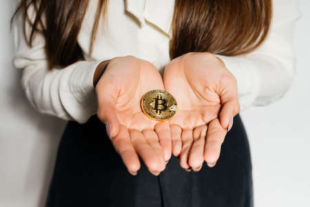 successful modern young girl holding a golden bitcoinの写真素材