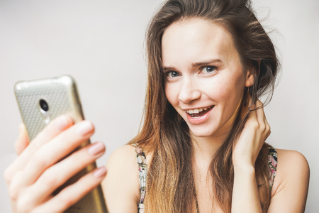 Happy smiling teen girl with mobile,looking something,doing selfieの写真素材