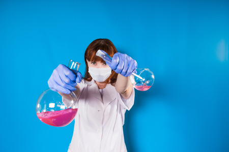 a woman in a white robe and wearing a mask poured the reagents from the flask into the flask, in...