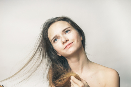 a young beautiful girl touches her long hair, dreamily looks somewhereの写真素材