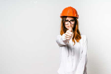 young red-haired girl in protective orange helmet showing thumb upの写真素材