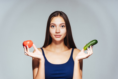 the girl on a gray background holds in hands vegetablesの写真素材