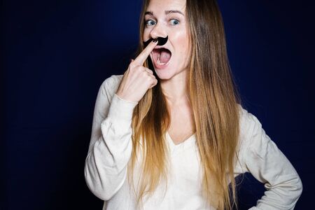 funny young beautiful girl with long hair attached to her face an overhead mustacheの写真素材