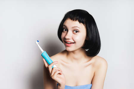 cute smiling girl with short black hair is holding a toothbrush in her handsの写真素材