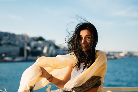 Funny girl in a scarf swims on a boat against the backdrop of the city in Istanbulの写真素材