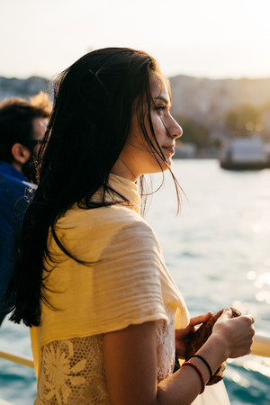 Pensive girl looking into the distance to the sunset cityの写真素材