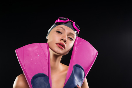 confident sports woman swimmer with a swimming cap on her head holds flippersの写真素材