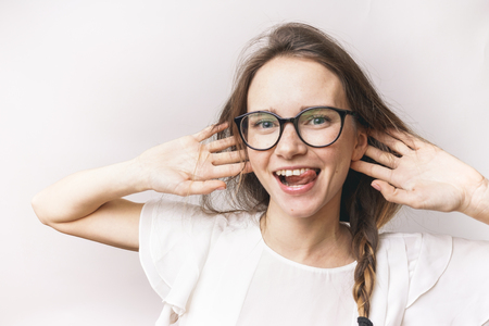 happy cute girl with glasses laughs and touches her hairの写真素材