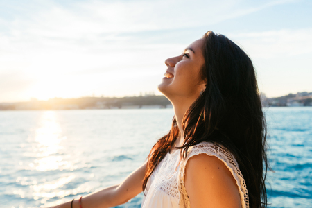 Portrait of a beautiful latin girl on a yacht at sunset and laughs, a ferry boat trip, luxury Istanbul travelの写真素材