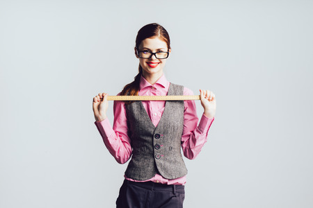 stylish happy girl in glasses and with red lipstick holds a ruler in hands, smilingの写真素材