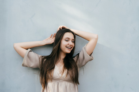lovely girl with long hair smiles and shrinks down. a lady in a beige dress is standing by the wallの写真素材