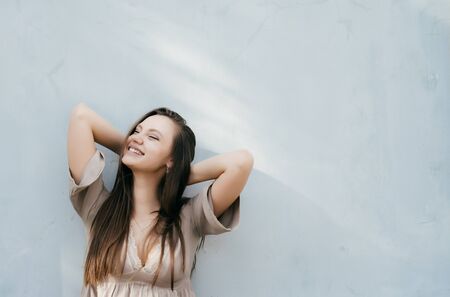 Young shine woman enjoy,happy smiling,copyspace,against the background of a light wallの写真素材