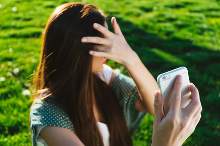 Woman doing selfie outside,copyspace. warm weather, green bright grassの写真素材