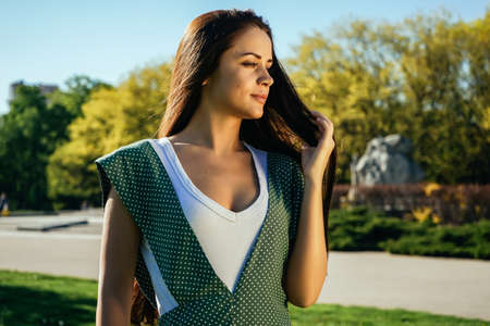 Girl in dress with white peas ,walks in the park, enjoys the sun and the weather
