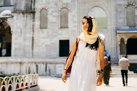 A young woman in a scarf stands near the mosqueの写真素材