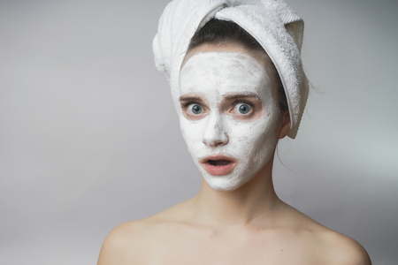Surprised woman gets white mask on the face,applying scrubの写真素材