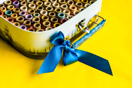 A multitude of multicolored thread bundles lie neatly in a box