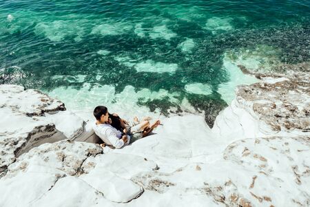A young couple of lovers lies in beautiful clear water near white rocks on vacationの写真素材