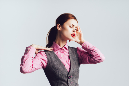 tired young girl in a pink shirt holds on to her head, headacheの写真素材