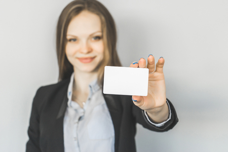 young smiling girl in black suit shows business cardの写真素材
