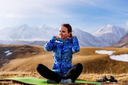 happy girl loves to travel, sits on the background of the Caucasian mountains, enjoys clean airの写真素材