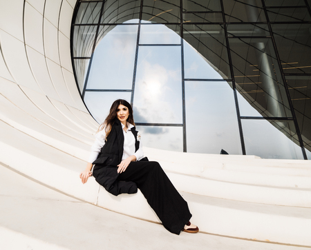 stylish business girl in a black suit posing near an unusual building in the city of Baku, Azerbaijanの写真素材
