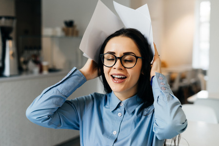 smiling successful business woman in glasses working in a cafe, freelancing, holding documentsの写真素材
