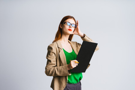 a serious business lady with bright red lips and with glasses holds folders in her hands and straightens her hair, isolatedの写真素材