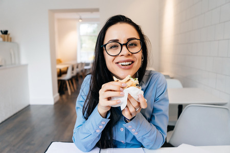 happy young business woman wearing glasses at breakfast in cafe, laughingの写真素材