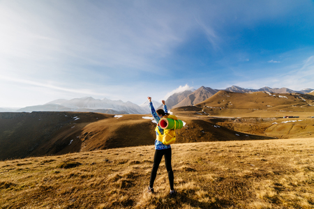 a sporty young girl in a blue jacket travels along the Caucasian ridge with a backpack and a tentの写真素材
