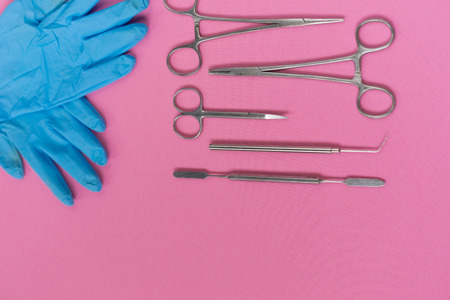 on a pink background are dental instruments and blue silicone glovesの写真素材