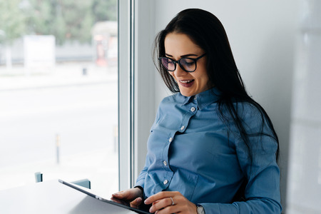 happy young girl with glasses working on laptop in cafe