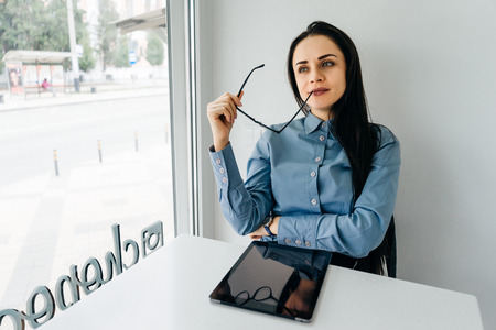 stylish young business woman in blue shirt thinks about workの写真素材