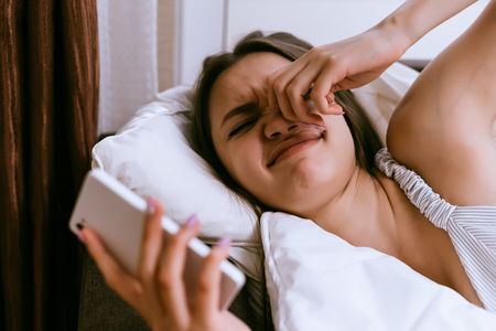 funny young girl woke up early, does not want to get up, turns off the alarm clockの写真素材
