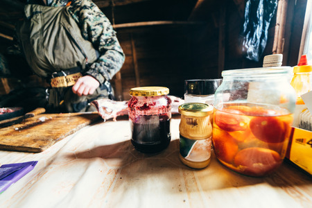 dine in a hunting lodge, on a wooden table cans with tomatoes and jamの写真素材