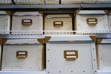 on the shelf are many white storage boxes