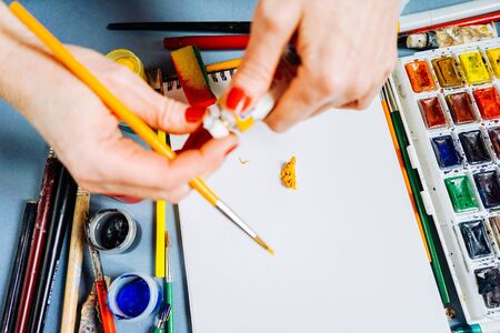 girl artist paints on white paper, watercolors and gouache, many brushesの写真素材