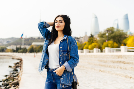stylish black-haired girl is traveling on vacation, posing against the backdrop of the architecture of the city of Bakuの写真素材