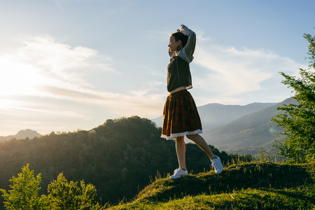 stylish girl in a dress enjoys nature, mountains and sun, meditatesの写真素材