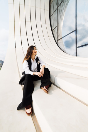 stylish girl in black suit posing against the background of an unusual building in Bakuの写真素材