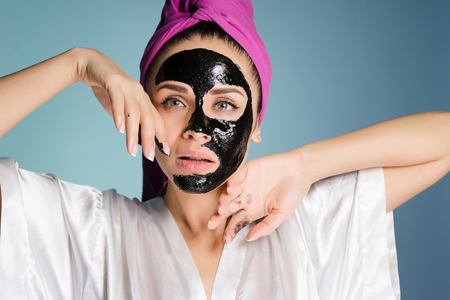 beautiful young girl with a pink towel on her head, on her face a black cleansing maskの写真素材