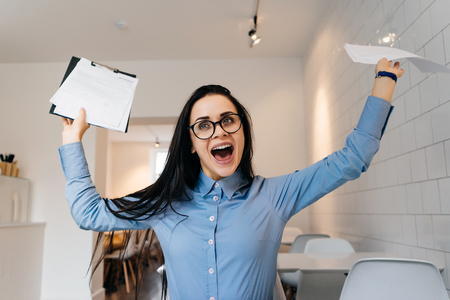 happy successful girl freelancer with glasses completed all the work, happy, keeps the documentsの写真素材