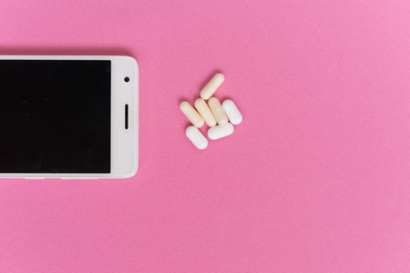 on a pink surface lies a white smartphone and tabletsの写真素材