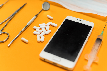 on the orange surface are dental instruments, a smartphone and tabletsの写真素材