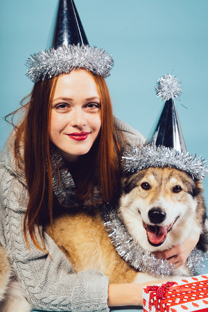 smiling red-haired girl celebrating the new year 2018 with her dog, silver tinselの写真素材