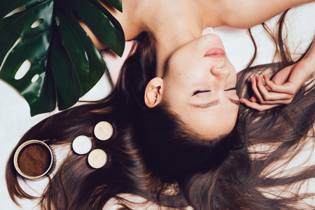 young long-haired girl lies, eyes closed, day of spa and relaxationの写真素材