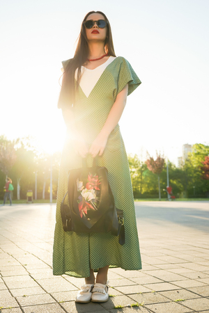 Fashion woman in glasses on street style with bag, sunsetの写真素材