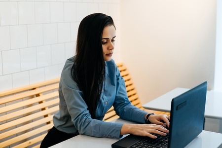 busy pensive girl brunette freelancer typing on laptop sitting in cafeの写真素材