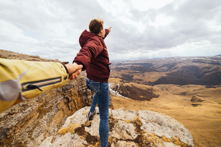 active young girl holding a guy by the hand, enjoying the Caucasian mountainsの写真素材